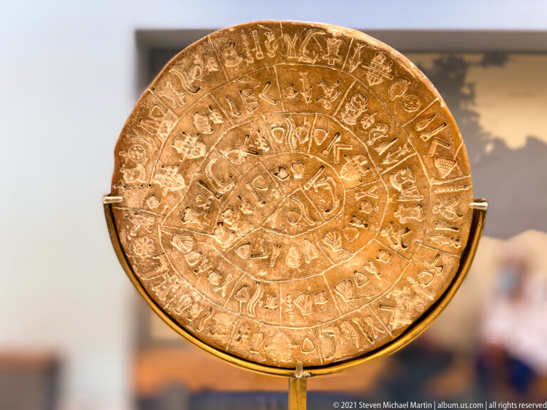 Round clay Phaistos Disc with stamped pictorial signs arranged in a spiral and divided into groups by incised lines.