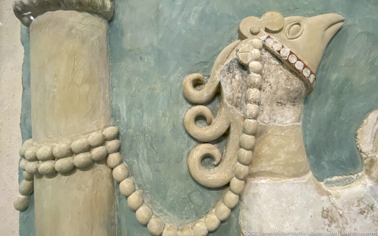 High-relief Minoan griffin tethered by a beaded cord to a column in a reconstruction from the Great East Hall at Knossos.