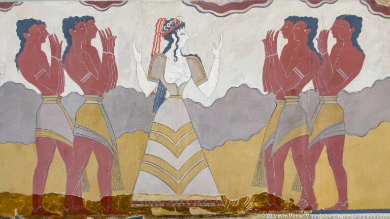 Central pale female figure in a long patterned skirt flanked by red male attendants in a reconstructed Minoan fresco.