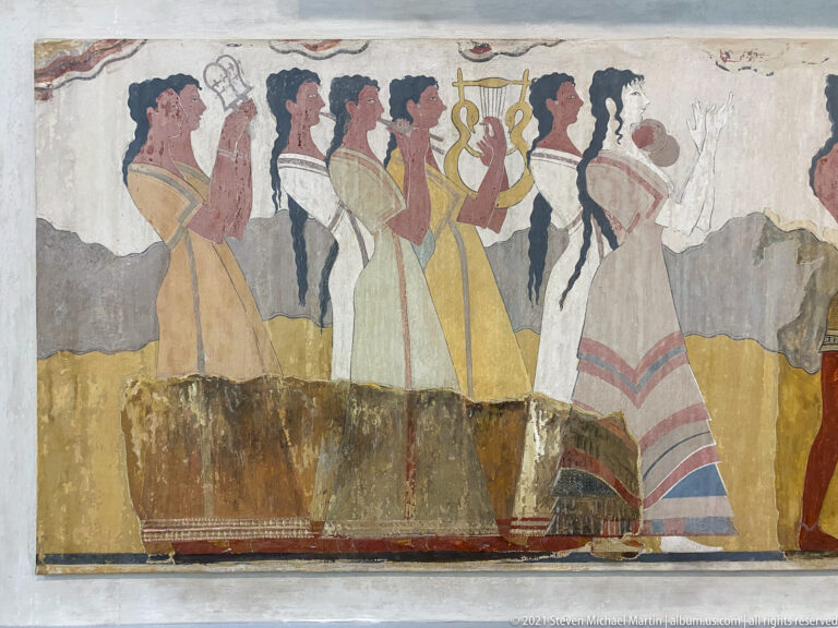 Reconstructed Procession Fresco from Knossos with elaborately dressed profile figures carrying or raising objects.