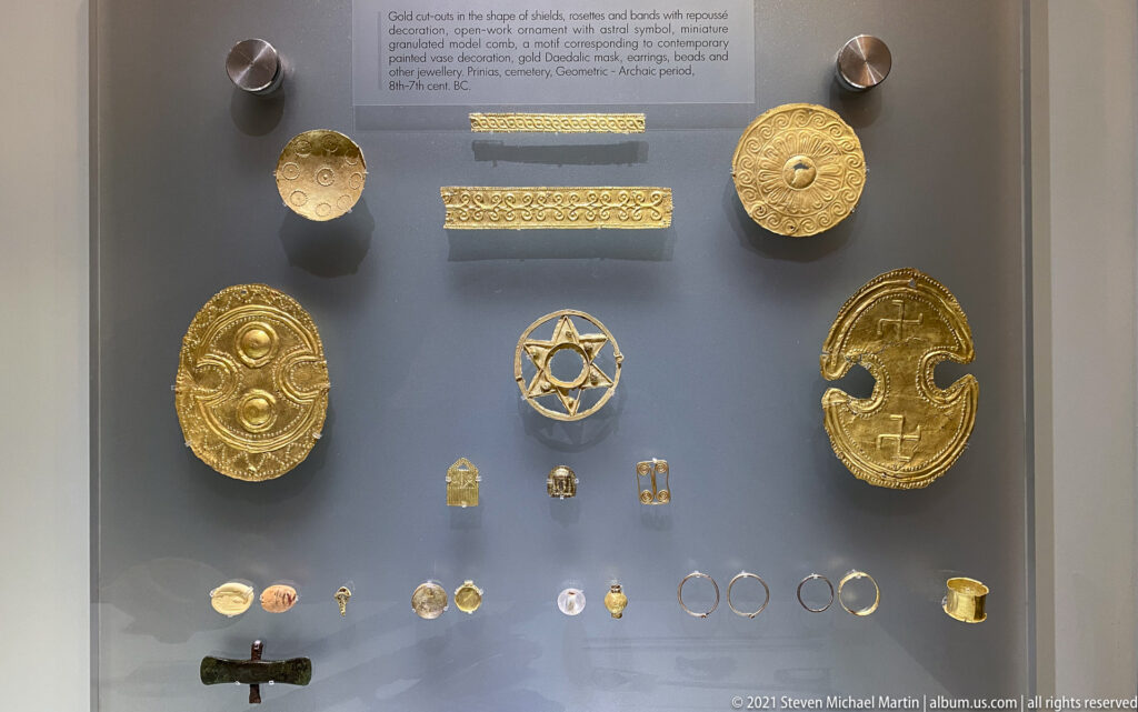 Close display of embossed circular gold plaques, patterned strips, a star-shaped openwork ornament, and a crescent-like gold sheet.