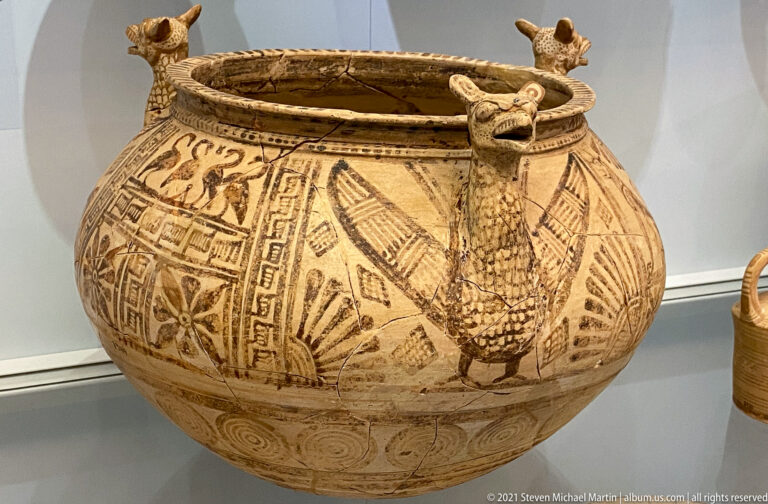 Large rounded painted vessel with geometric panels and a projecting long-necked bird figure attached below the rim.