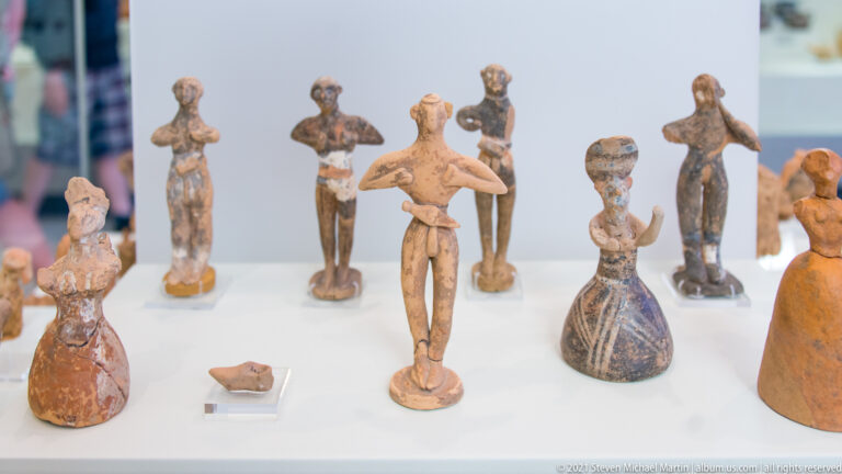 Group of small standing terracotta human figurines, several with dark painted details and varied garments.