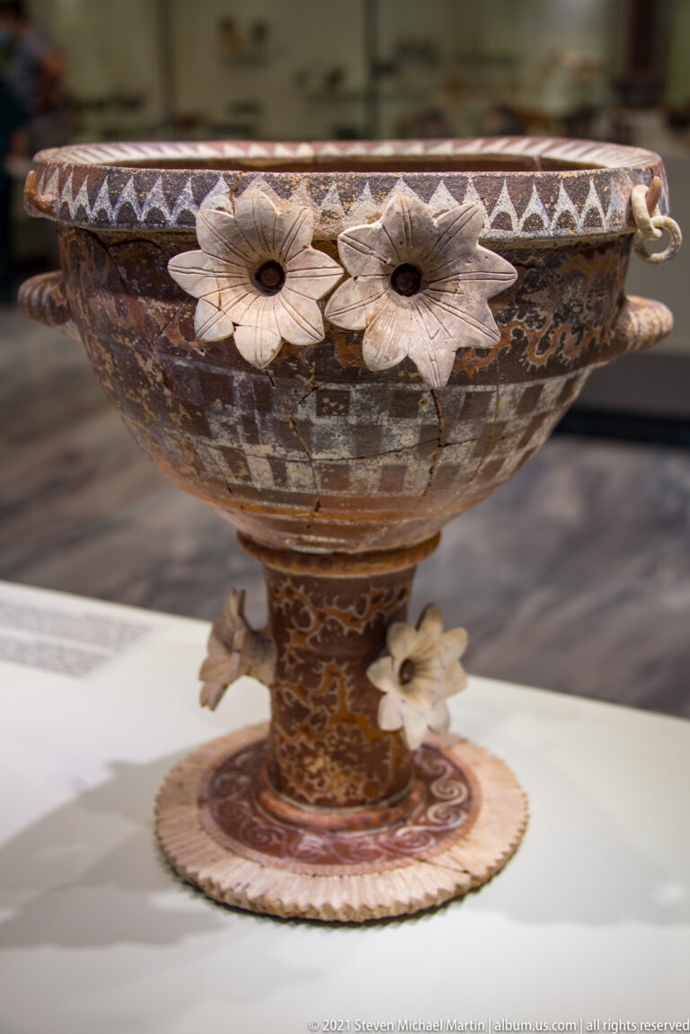 Large painted pedestal bowl with applied pale rosettes around the rim and stem and small side handles.