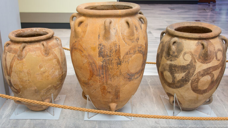 Three large ceramic storage jars with broad mouths, small shoulder handles, and painted looping motifs.
