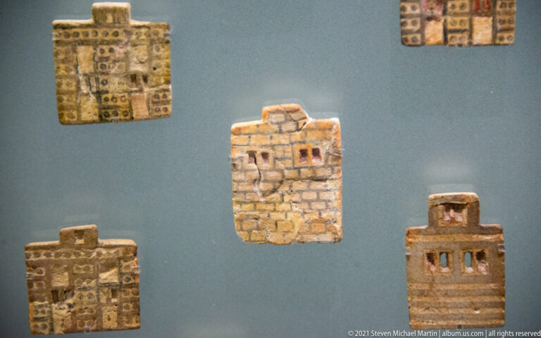 Four rectangular clay tablets with incised signs, including a central fragment divided into a dense grid.