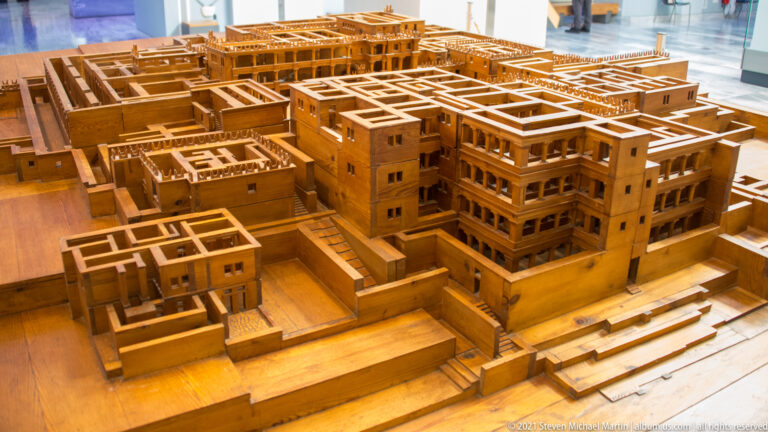 Oblique elevated view of wooden Minoan palace model with multi-story blocks, courts, passages, and stairways.