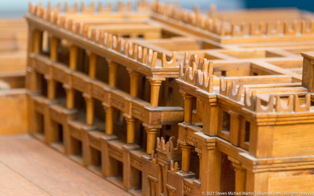 Detailed wooden palace model with rows of columns, upper galleries, parapets, and narrow courts between reconstructed buildings.