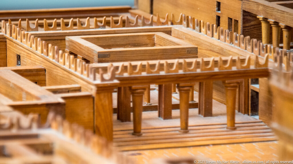 Close view of a wooden architectural model with a square columned court, surrounding rooms, corridors, and multiple floor levels.