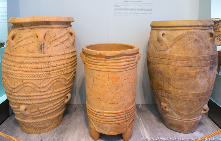 Three tall Minoan storage jars with broad mouths and varied applied, ridged, incised, and impressed decoration.