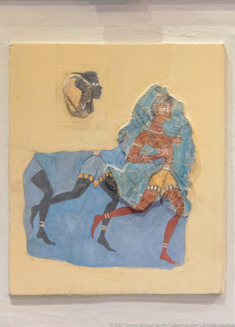 Minoan fresco fragment showing a profile human figure beside or above a dark animal against a blue background.