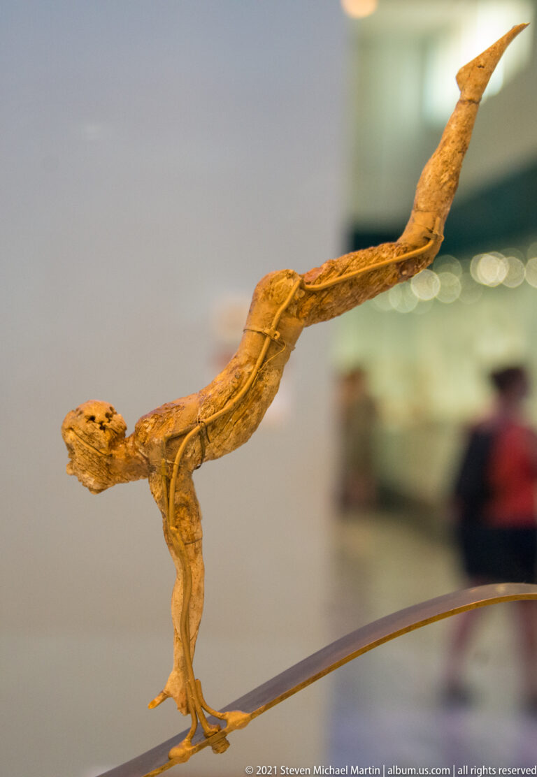 Ivory Minoan bull-leaper figurine with elongated body and one leg extended high behind during an acrobatic leap.
