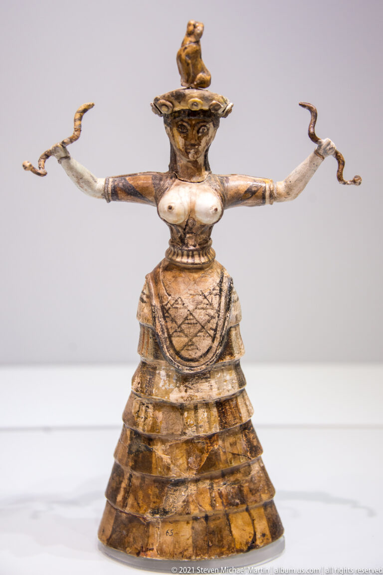 Painted-faience Minoan Snake Goddess from Knossos with exposed breasts, fitted bodice, flounced skirt, and snakes.