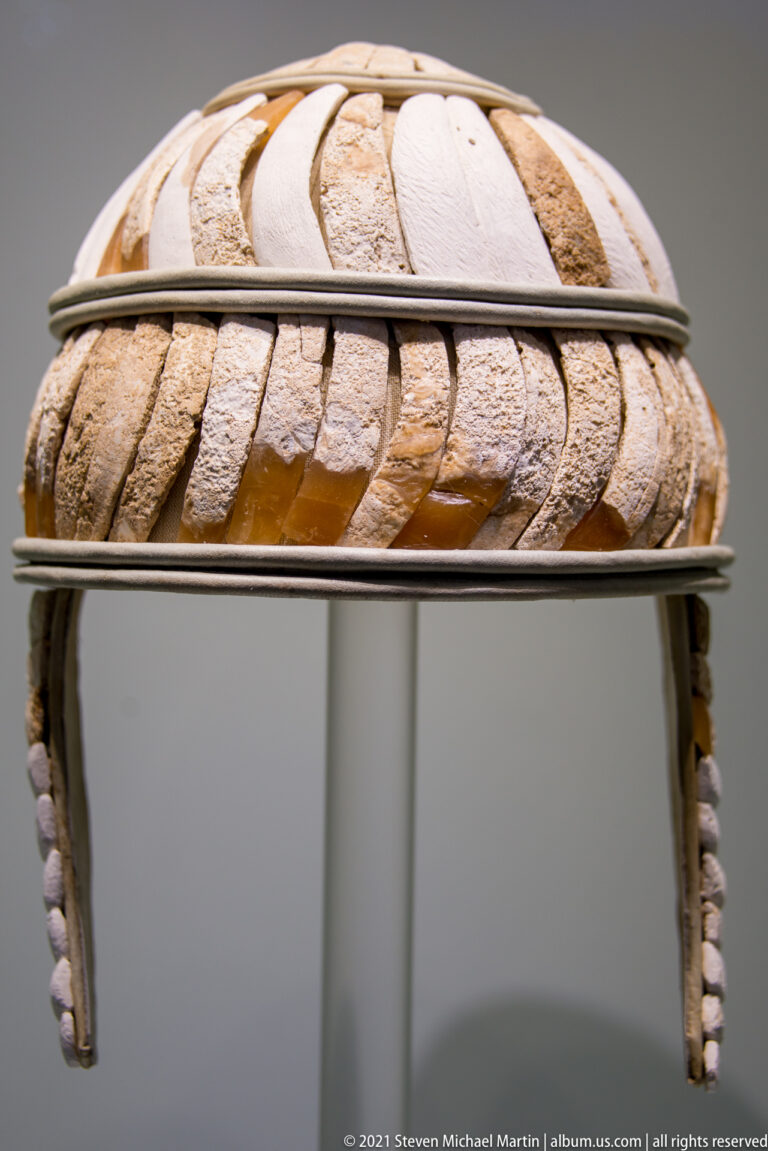 Reconstructed Bronze Age boar’s-tusk helmet covered with overlapping pale tusk plaques and fitted with cheek guards.