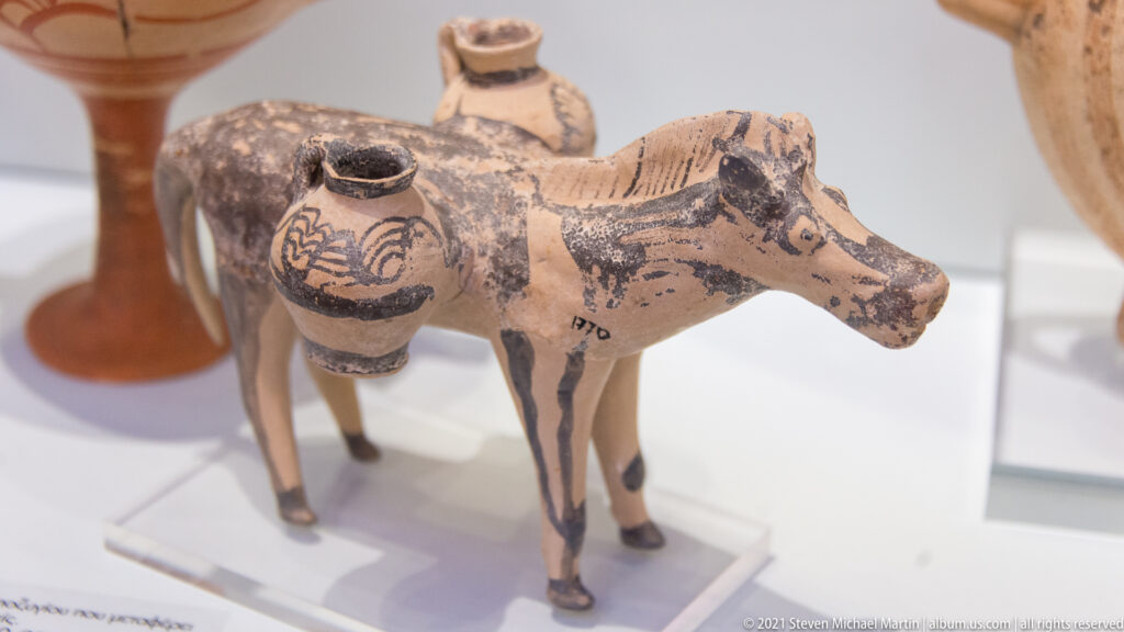 Painted bull-shaped ceramic vessel on four legs with multiple small jar-like openings attached to its body.