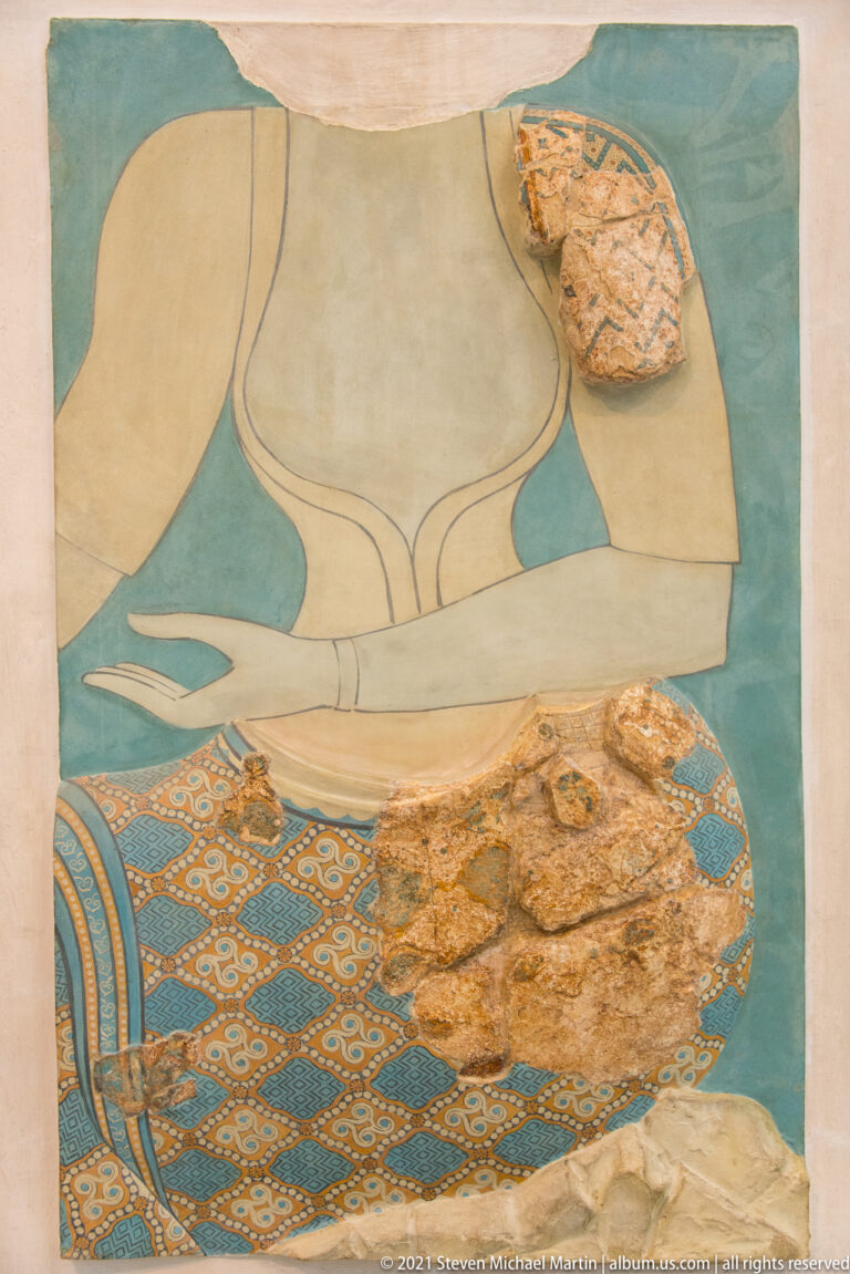 Reconstructed seated female figure on a blue ground with original fresco fragments preserved across the arm and patterned textile.