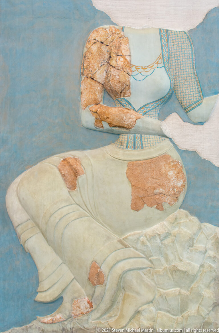 Reconstructed Minoan fresco with two female figures on a blue ground and surviving plaster fragments in faces, arms, and clothing.