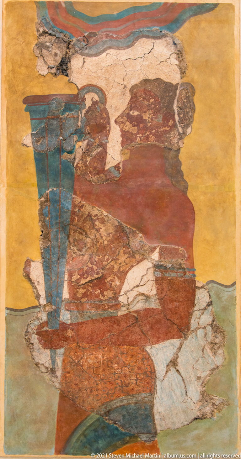 Fragmentary Minoan fresco of a seated reddish-brown male figure holding a tall blue vessel or staff against an ochre background.
