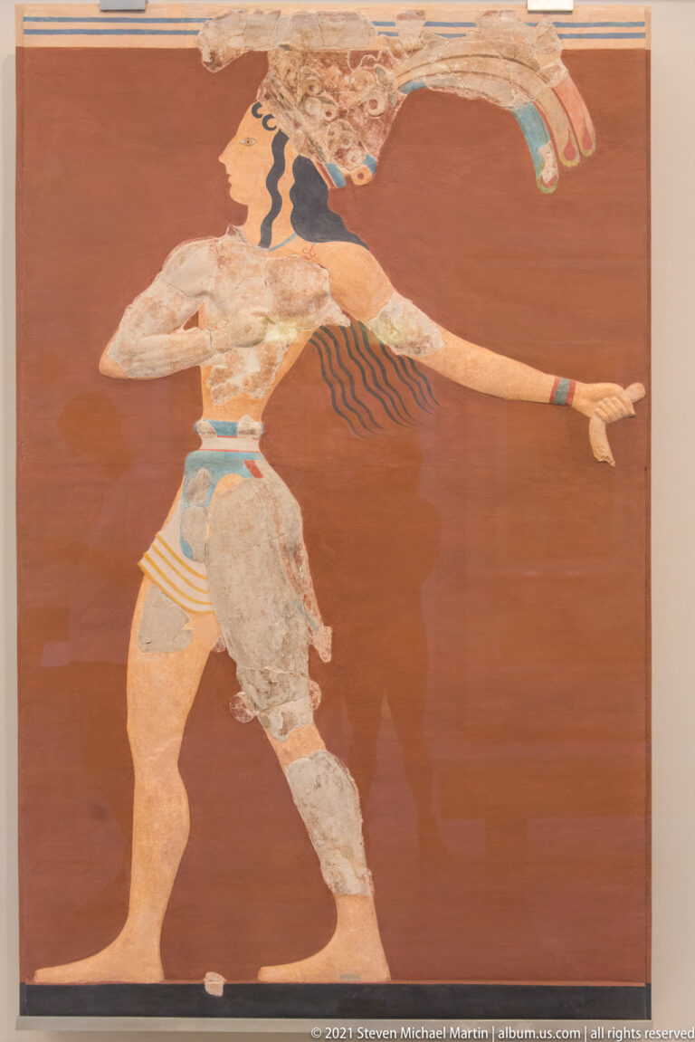 Reconstructed Minoan fresco of a youthful male figure running across a red ground with one arm extended forward.