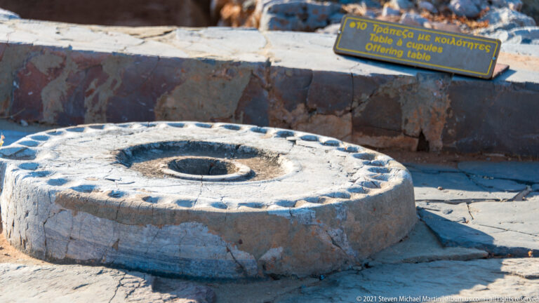 Circular stone offering table with small cup-holes around the rim and a larger central depression.