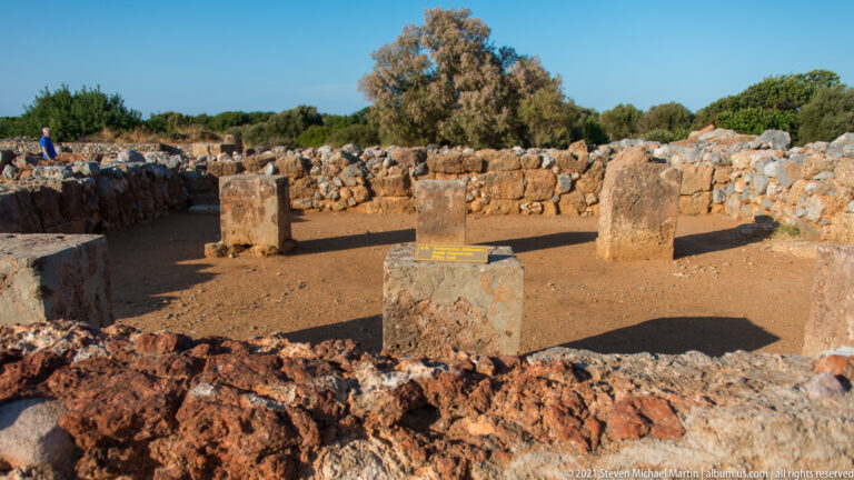 Four rectangular stone supports standing in a low-walled excavated space at Malia.