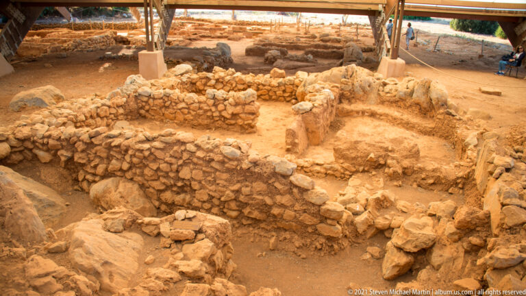 Dense cluster of small stone-walled rooms and passages viewed from above beneath a protective roof.