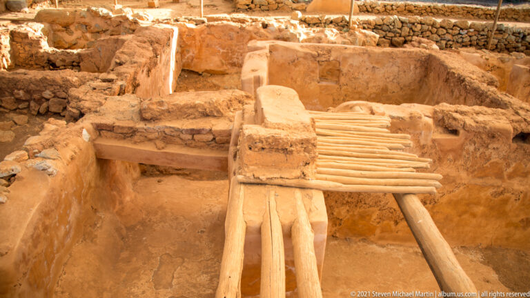 Small excavated room with reconstructed horizontal cylindrical elements spanning between low wall sections.