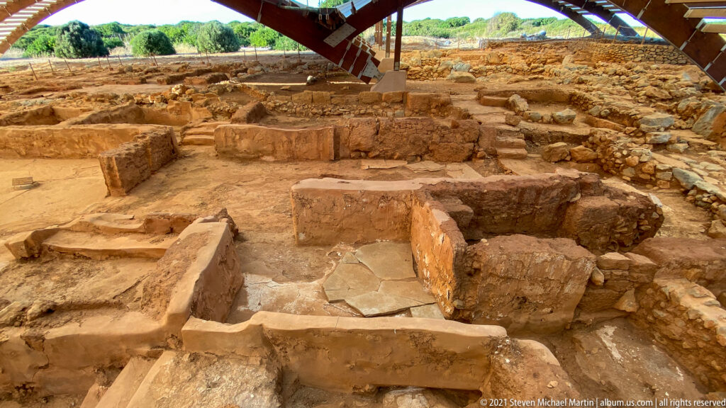 Low stone walls divide excavated rooms with surviving paved floor patches at Malia Minoan Palace.