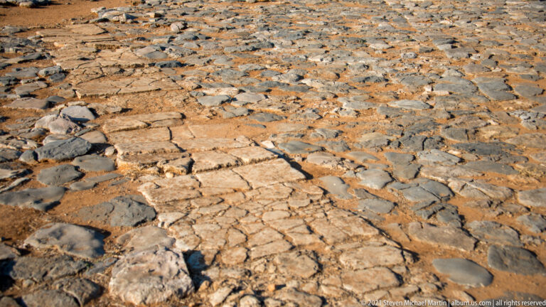 Ancient stone paving with irregular dark stones and a central band of larger pale slabs.