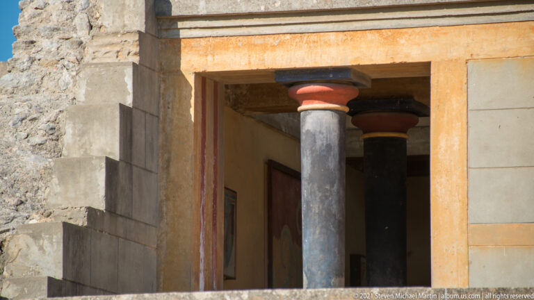 Reconstructed doorway at Knossos with a dark tapered column, red capital, pale walls, and a second column inside.