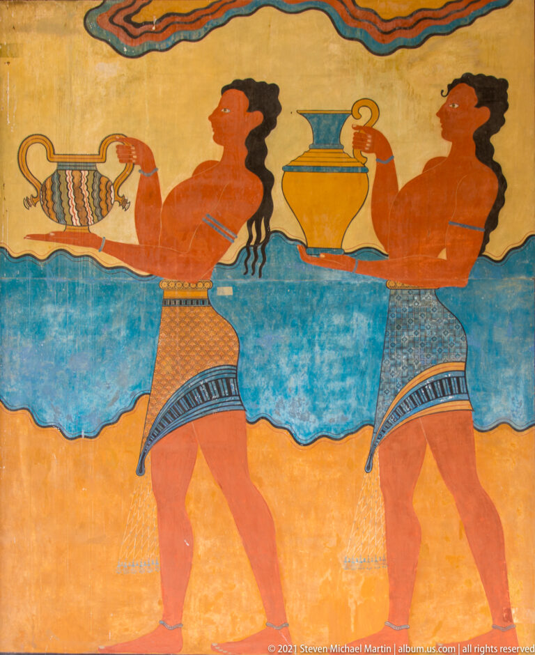 Two reconstructed Minoan cup-bearers carrying large vessels in profile, with patterned garments and a broad blue background band.