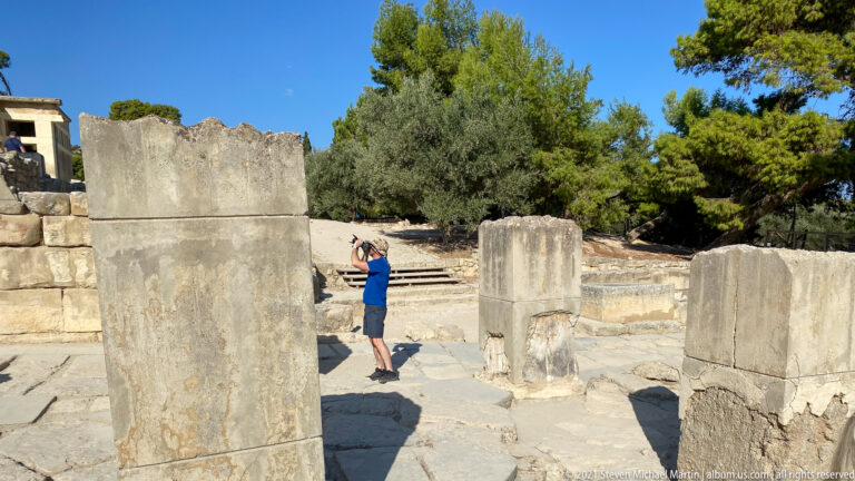 Tall pale stone piers in an excavated area, with a visitor standing behind them for scale.