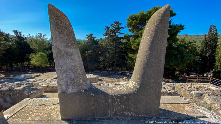 Large stone Horns of Consecration rising above the ruins and trees at the Palace of Knossos.