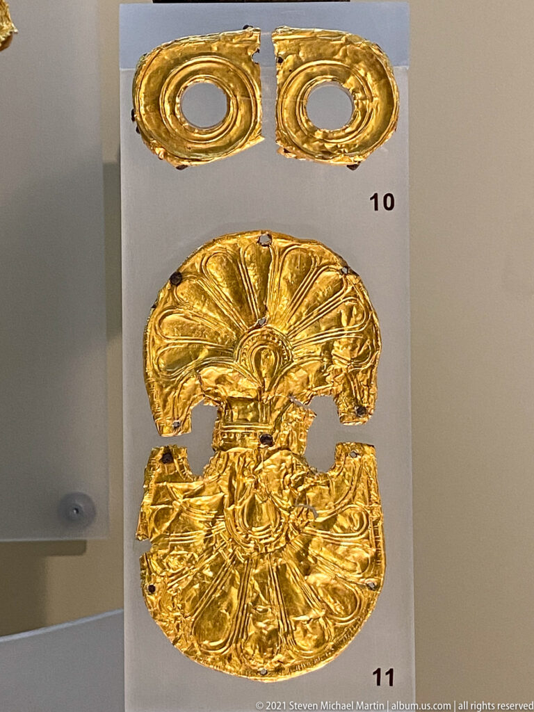 Small embossed gold ornaments, including paired rings and larger circular plaques with radiating floral decoration.