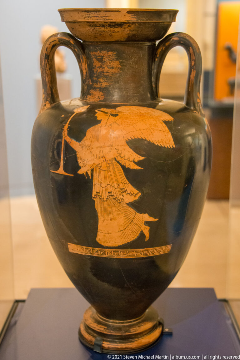 Black-glazed red-figure column krater with a large orange-red winged figure painted on the body.