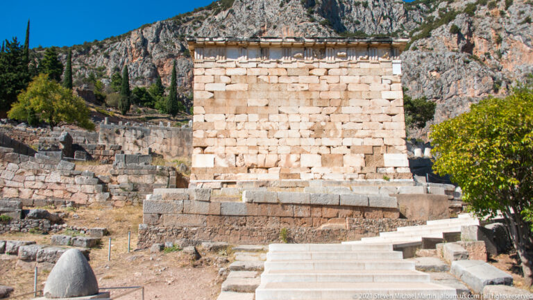 Reconstructed pale-stone Treasury of the Athenians with stepped base and entablature beside the Sacred Way at Delphi.