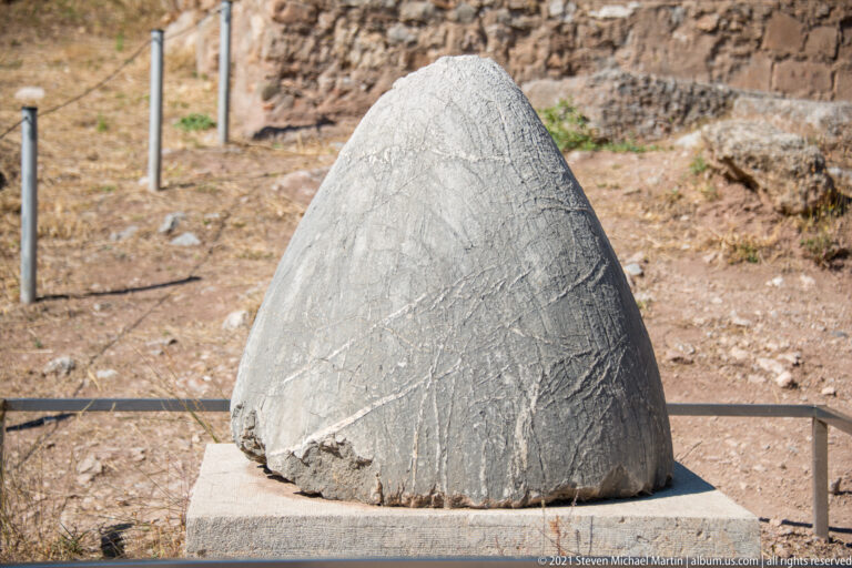 Conical weathered stone on a low base, its surface covered with a faint intersecting net-like pattern.