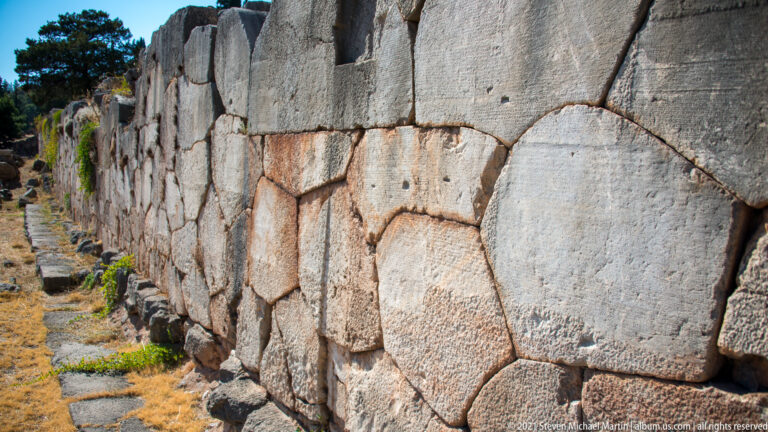 Close oblique view along a retaining wall of large, tightly fitted irregular polygonal stone blocks.