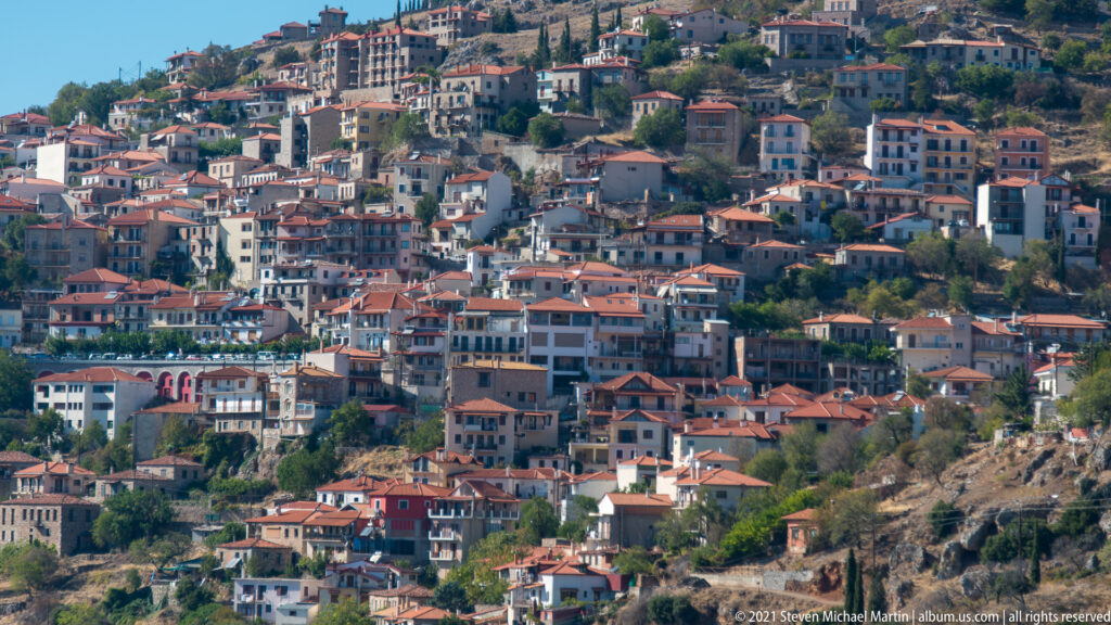 Dense hillside town of white buildings and red tile roofs stepping down the mountain slope at Delphi.