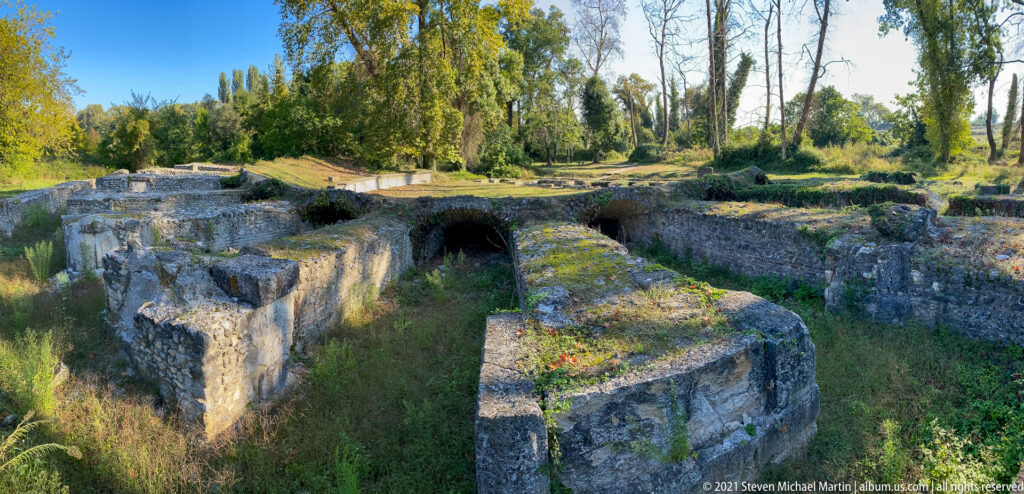 Deep stone chamber with thick walls, mossy surfaces, and a dark arched opening beneath trees at Dion.