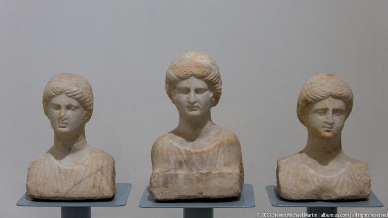 Three small marble female busts displayed in a row, each with individualized hair, facial features, and draped shoulders.