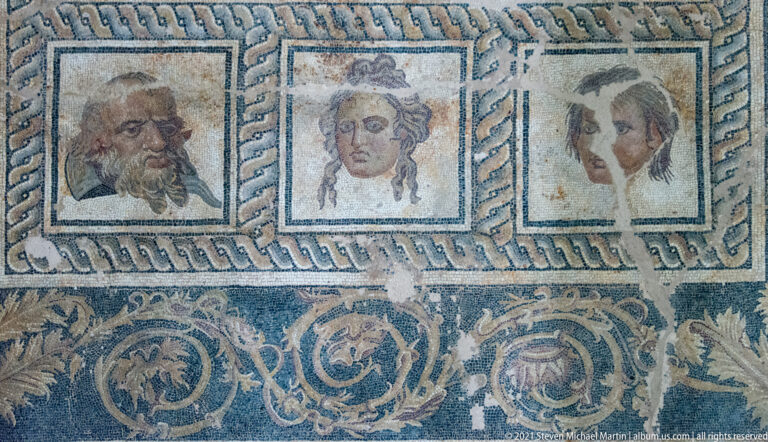 Three theatrical-mask mosaic panels within the decorative border of the Epiphany of Dionysus pavement.