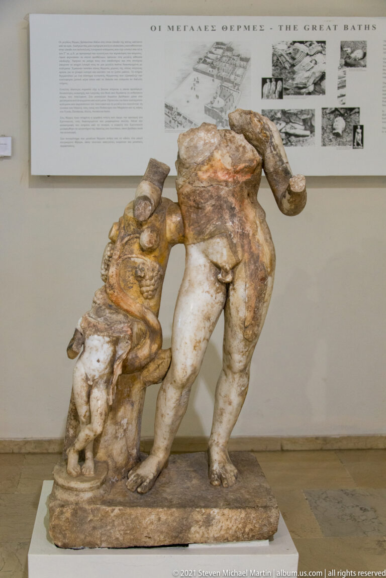 Fragmentary marble group with a large nude male torso and a smaller figure leaning against him on a shared base.