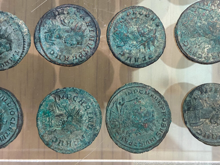 Group of green-patinated Roman bronze coins with worn portraits, figures, architectural reverses, and partial Latin inscriptions.