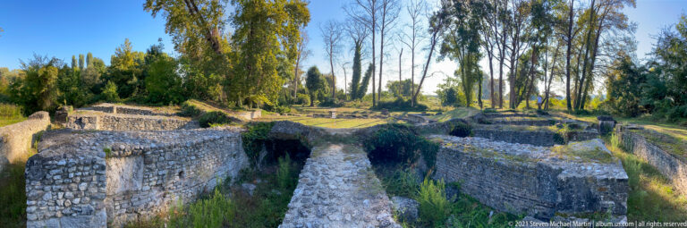 Deep stone-built chambers and long wall corridors covered with grass and moss beneath tall trees at Dion.