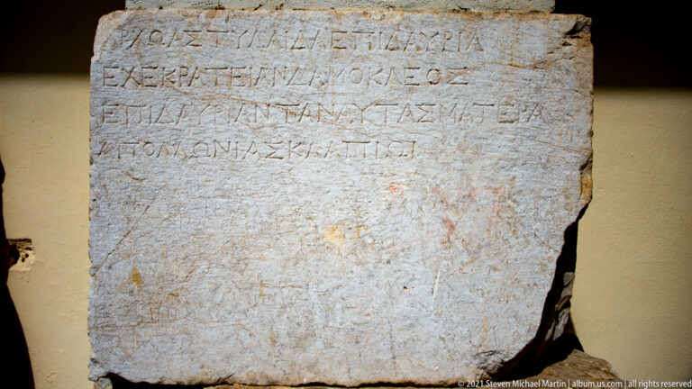 Rectangular pale stone block with several lines of large incised ancient Greek letters.