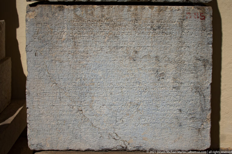 Large rectangular stone covered with many closely spaced lines of faint incised Greek text.