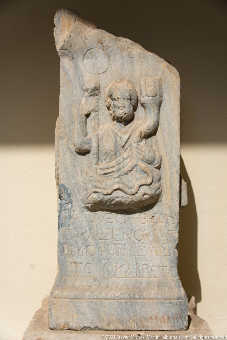 Small stone relief with a reclining or seated figure above several lines of Greek inscription.