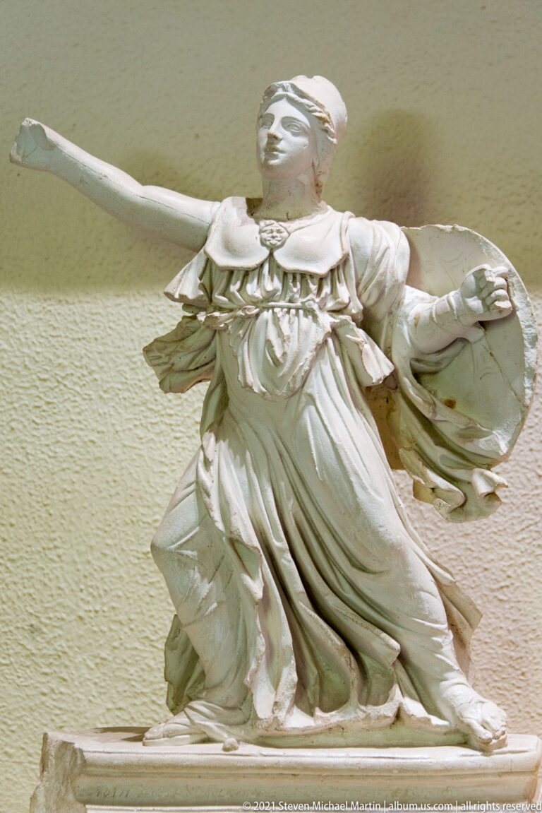 Fragmentary winged female marble figure in a dynamic pose with outstretched arms and billowing drapery.