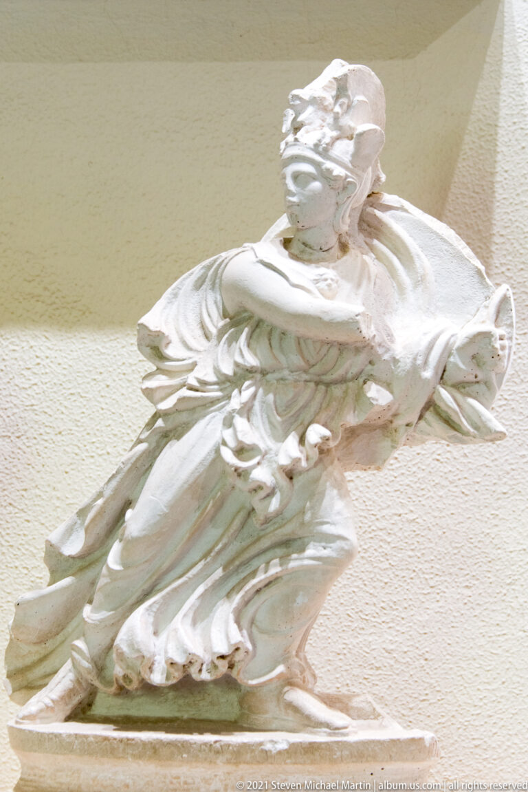 Fragmentary reclining marble figure with upturned head and deeply folded drapery sweeping across the body.